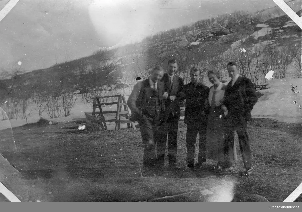 Fem personer, fire menn og en kvinne står ute på en gårdsplass eller i en hage. Til høyre i bildet står Randi og Otto Møller.