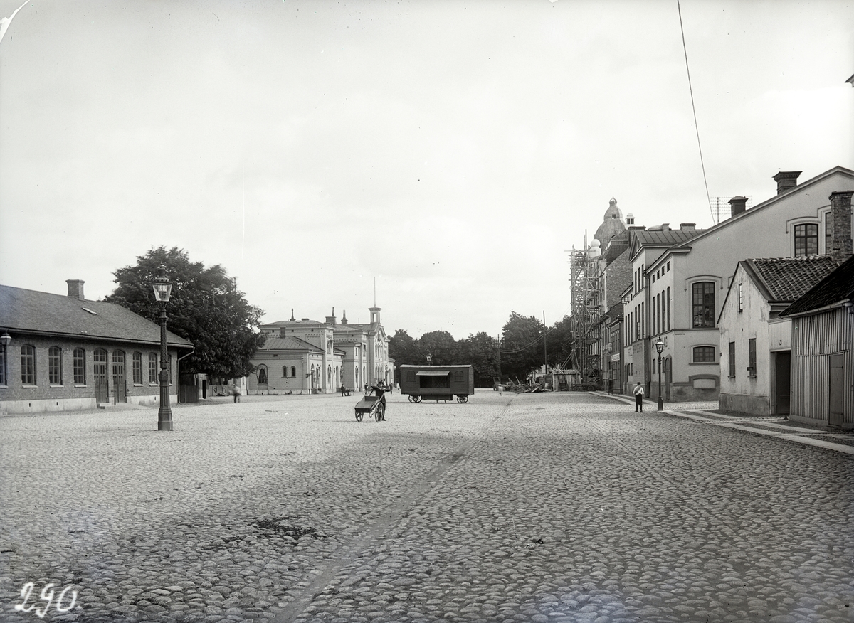 Järnvägstorget från väster i Jönköping. Mitt på torget står fiskhandlare K. E. Svenssons vagn. Längst bort till höger byggs Telegrafhuset. Till vänster syns järnvägsstationen och godsmagasinet. I hörnet vid Barnarpsgatan låg Krönleins bryggeri med anor från 1800-talets mitt.