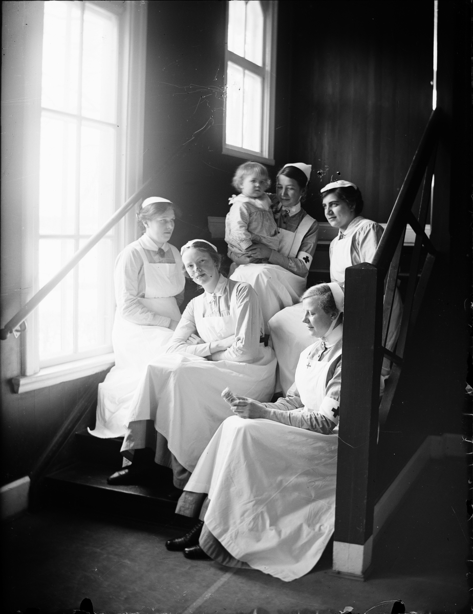 Sjukvårdspersonal och ett barn sitter i trappa, Östhammars lasarett, Uppland