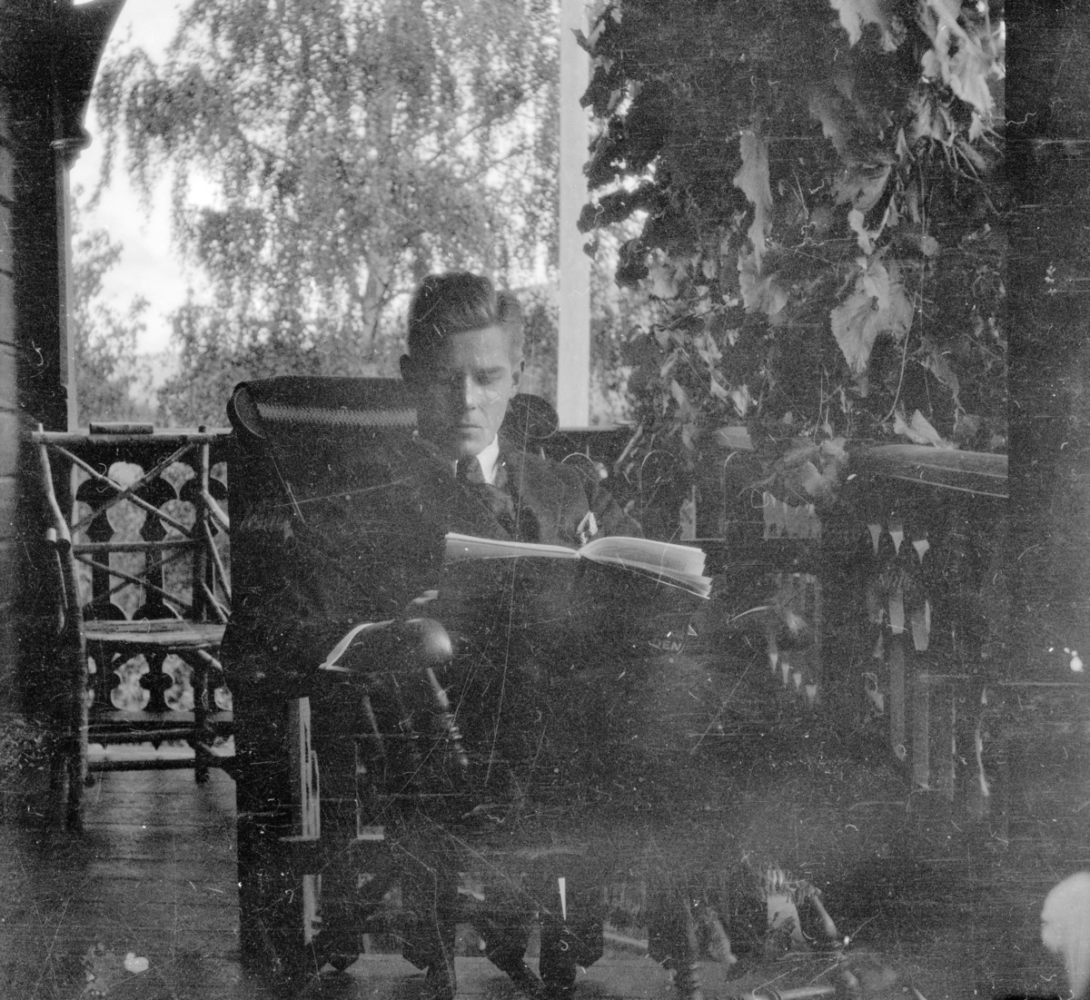 Mann sitter og leser på veranda.