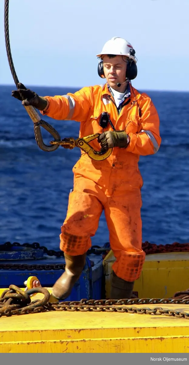 Hans Jacob Hevrøy fester wire på en konteiner som skal losses fra forsyningsfartøyet Viking Troll.
Han er i kontakt med kranføreren via kommunikasjonsutstyr.