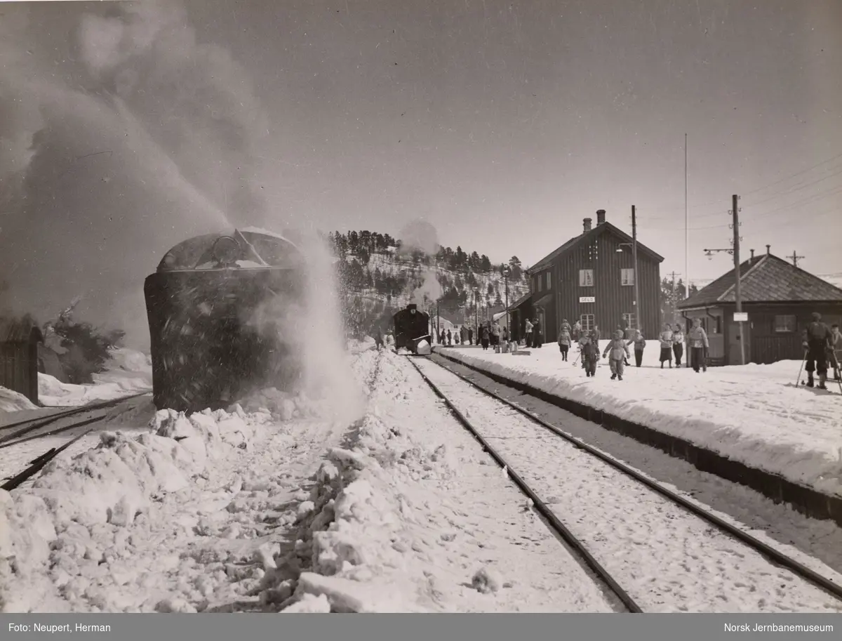 Roterende snøplog i aksjon på Geilo stasjon, damptog kjører inn i spor 1