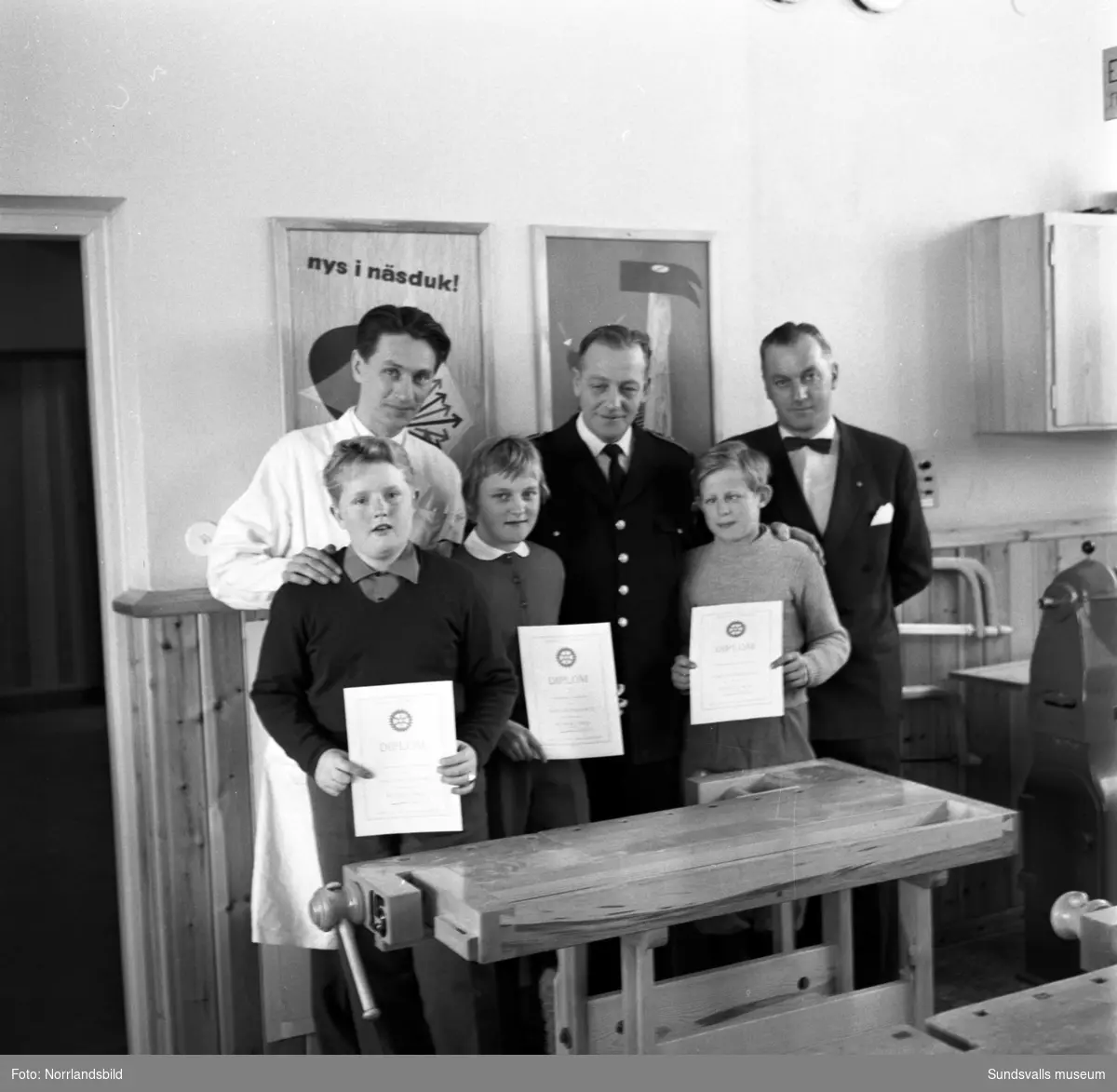 Rotary delar ut diplom till väluppfostrade barn. Tre barn i en slöjdsal visar upp sina utmärkelser.