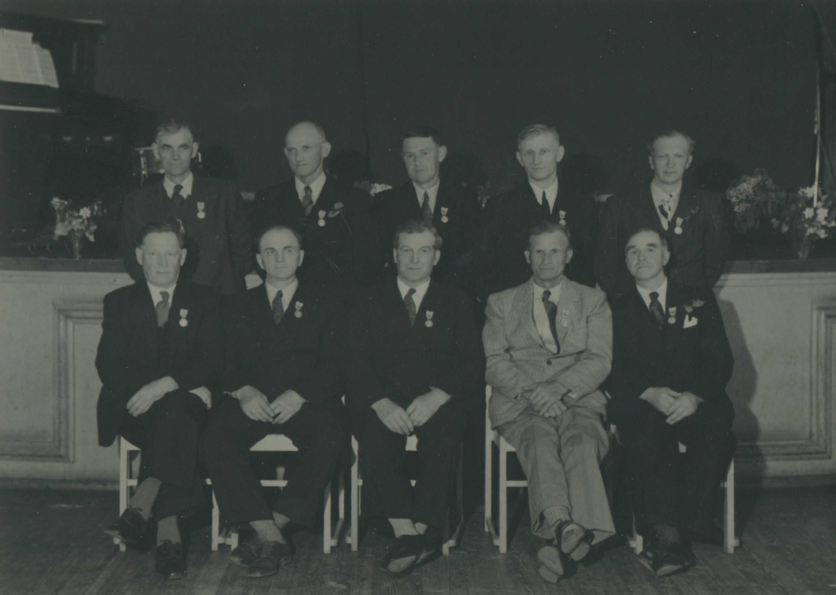 Gruppebilde av 10 menn dekorert med Det Kongelige Selskap for Norges Vels medalje for lang og tro tjeneste.