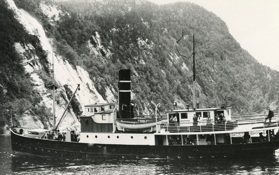 Motivet viser DS OSTER (bygget 1908) i kystlandskap.