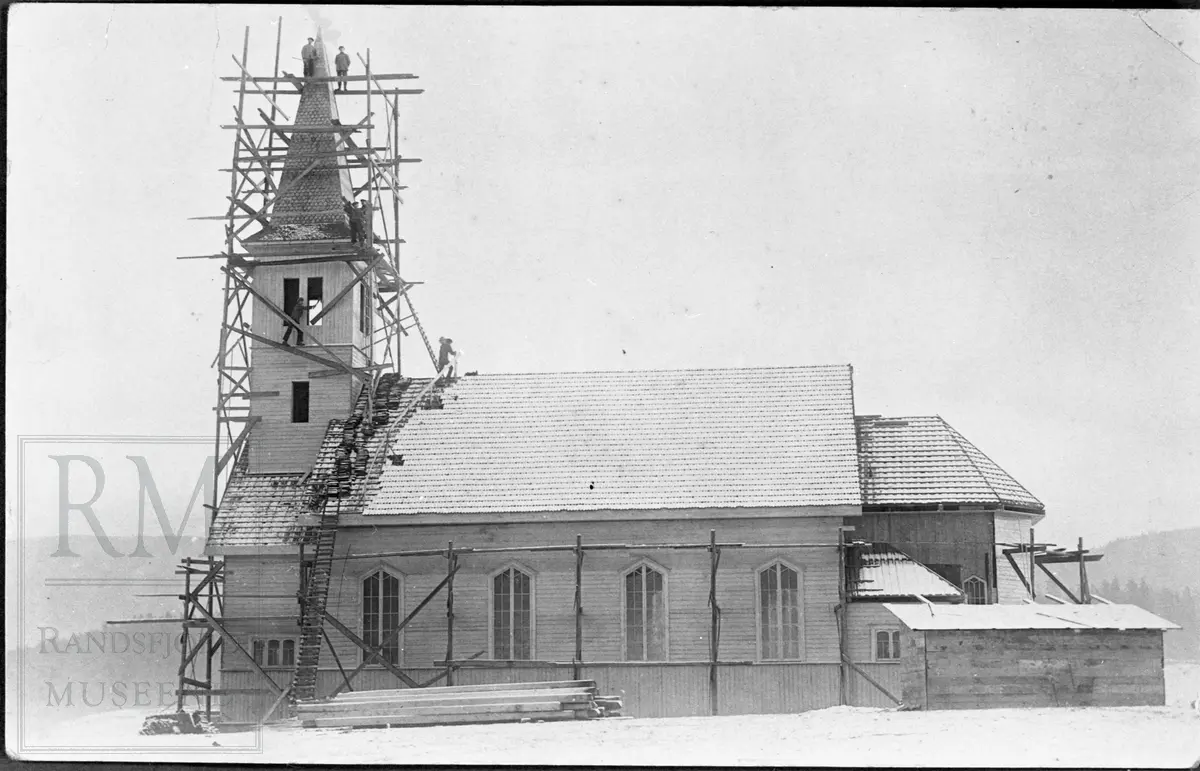 Bygging av Randsfjord kirke. Arbeidere på stillas rundt tårnet.