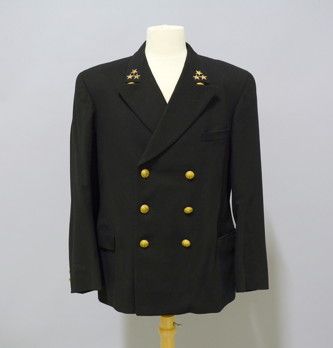 Uniformsjakke til Telemarksbåtene. Sort uniformsjakke i ull. Kraven har tre påsydde stjerner på hver side. Foran er det tre stk knapper med anker på hver side av åpningen, samt to lommer med klaff og brystlomme.