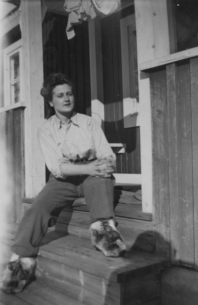 Porträtt av Birgit Johansson, sittandes på en veranda. Birgit var luftbevakerska stationerad vid 91:a ls-kompaniet i Tellejåkk, Kåbdalis 1942.