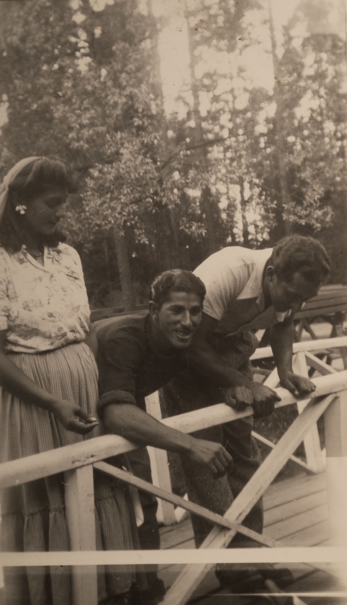 En romsk kvinna och två män står vid ett staket i Stadsparken, Falun augusti 1950.