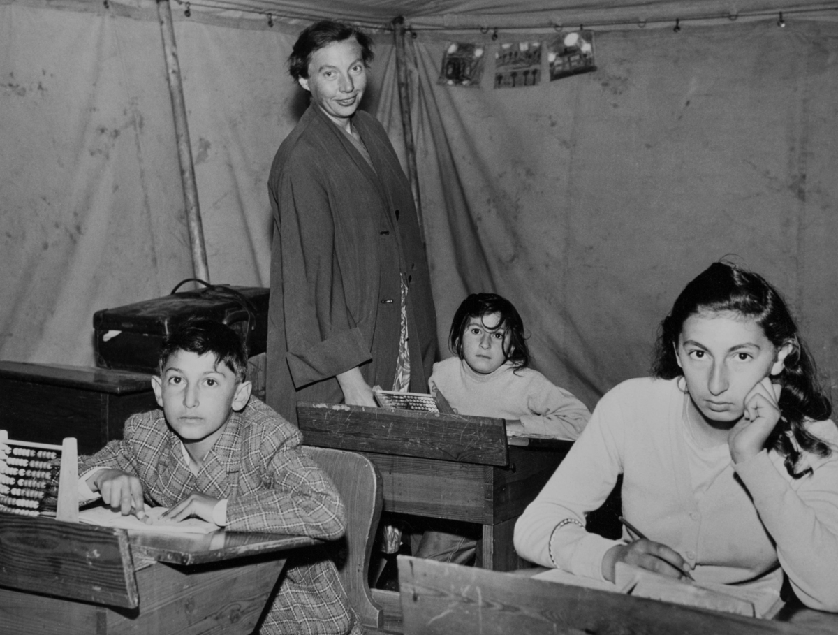 Tre elever sitter i sina bänkar i skoltältet under romska sommarskolan 1958 i Hägersten.