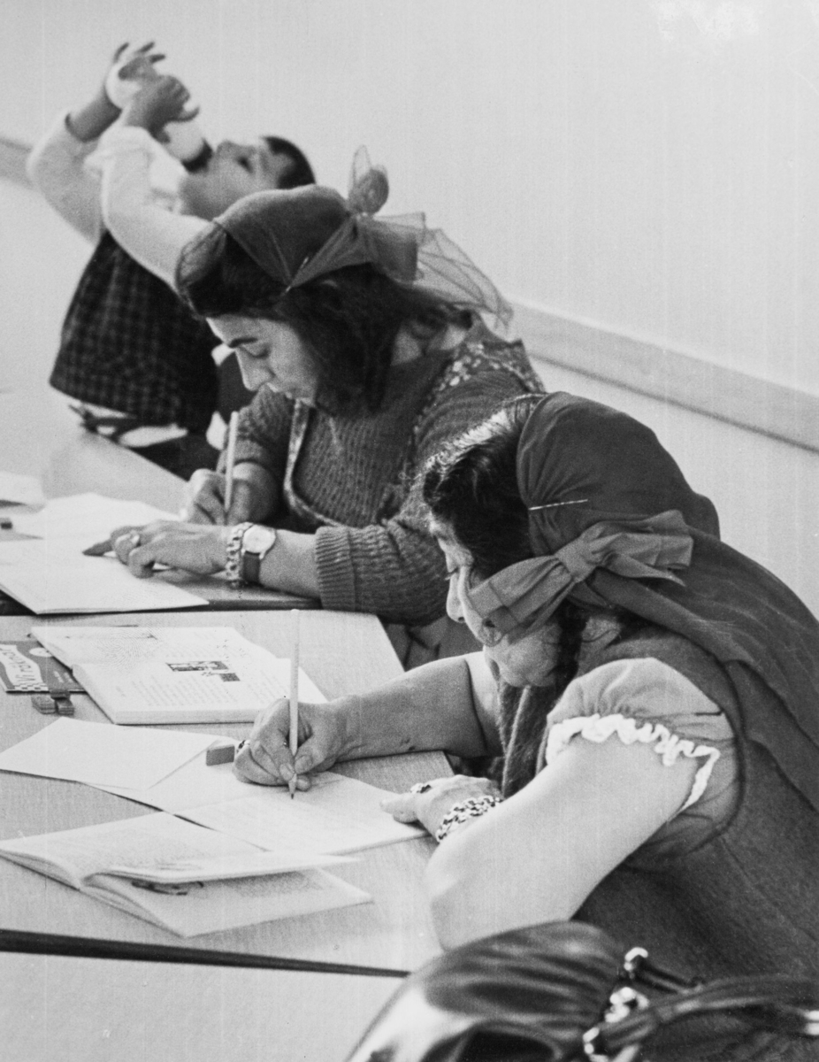 Några romska kvinnor sitter i en skolbänk vid vuxenutbildning.