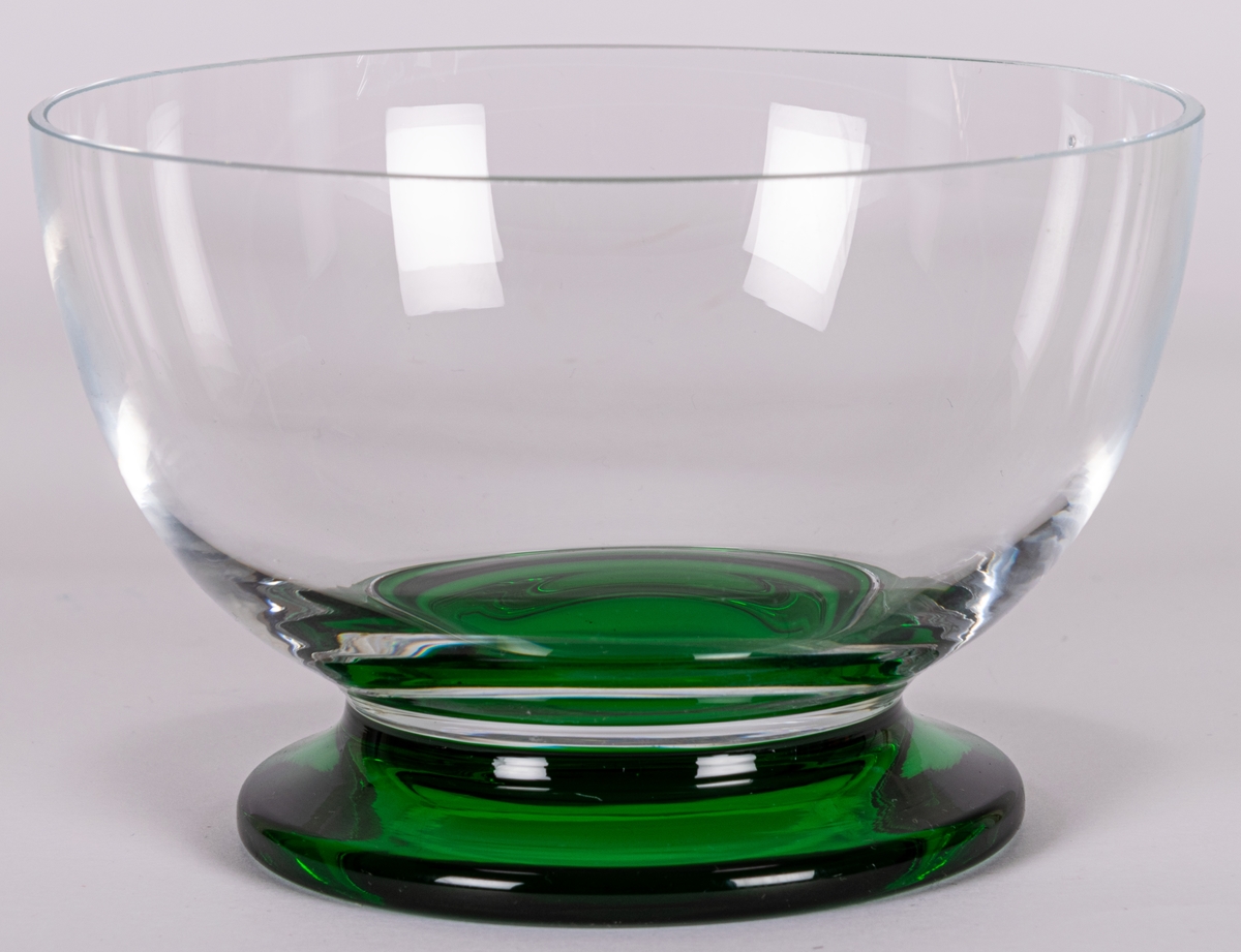 Skål, modell "Brazil". Halvsfärisk, ofärgad på låg, utkragad fot i grönt glas. Design Gunnar Cyrén för Orrefors Glasbruk.