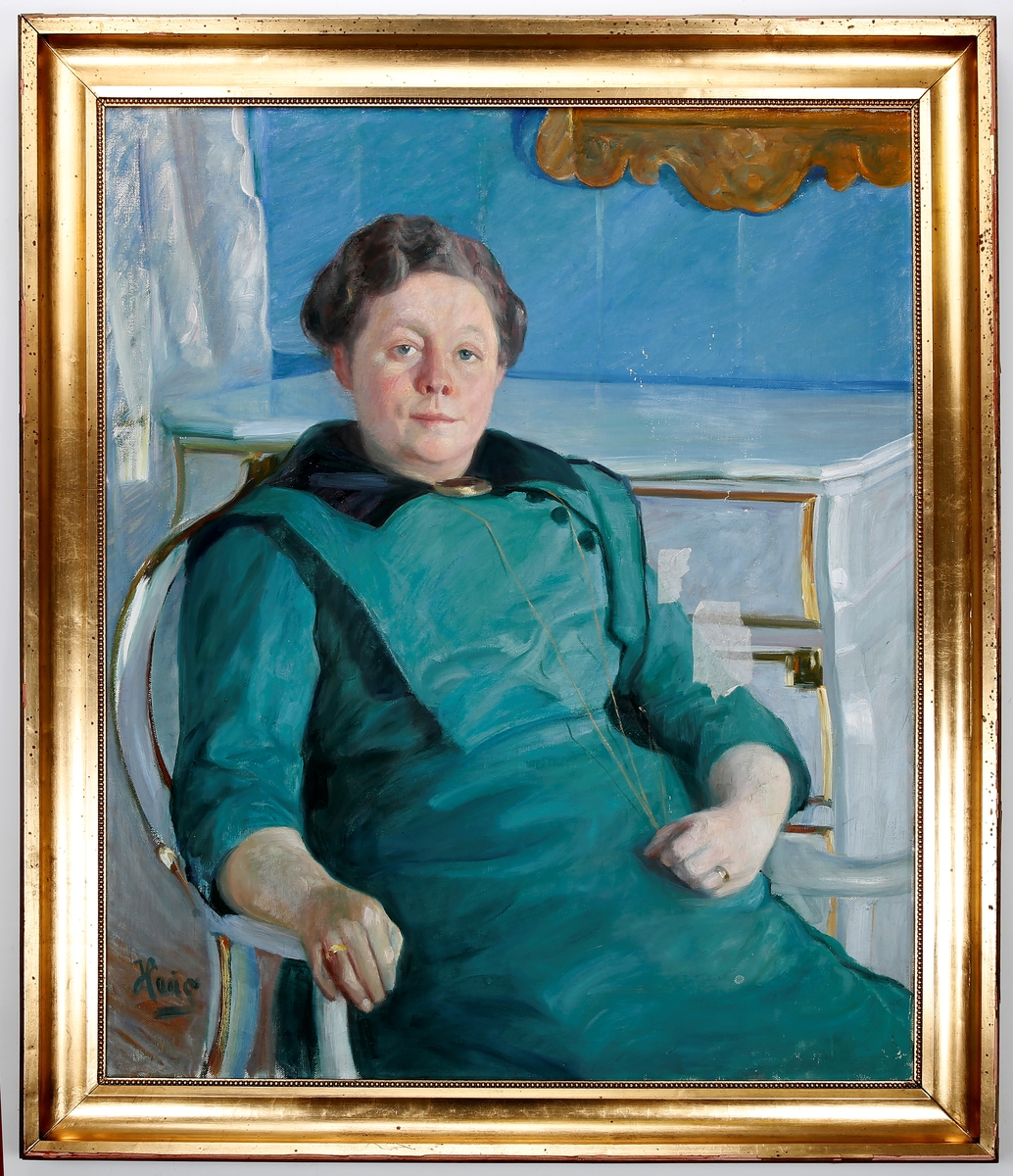 Portrett av Gyda Løken, sittende, kommode i bakgrunnen.