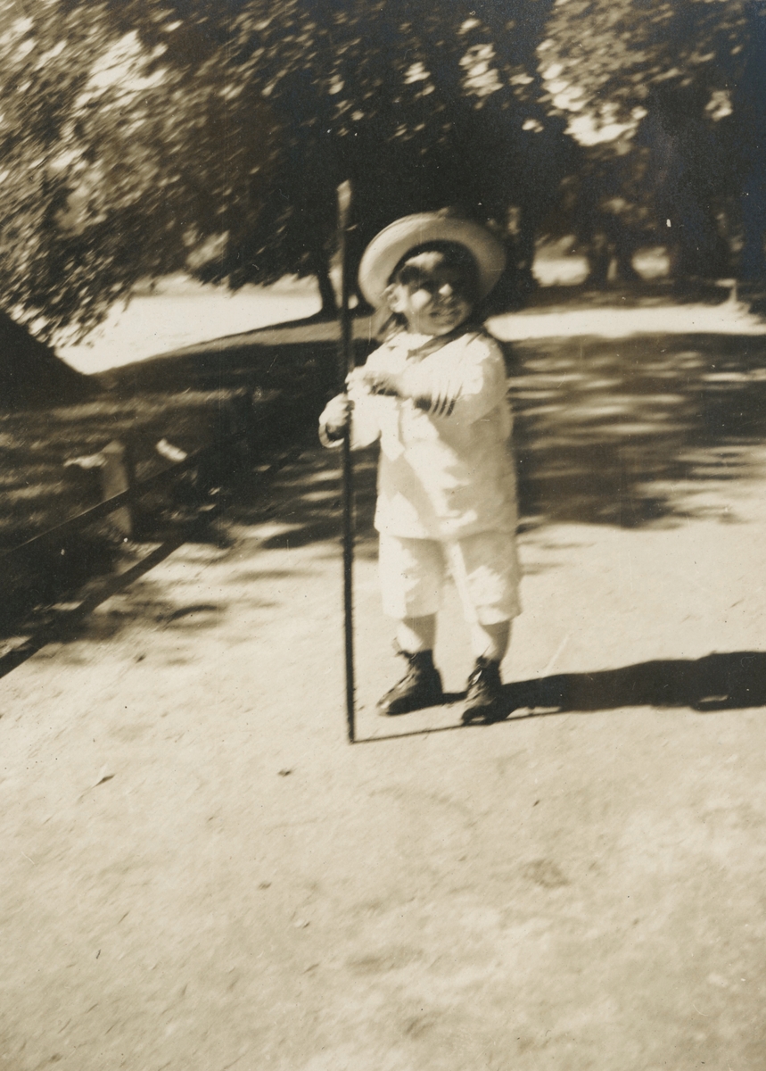 Portrettfotografi av et lite barn med matrosklær og en stav.