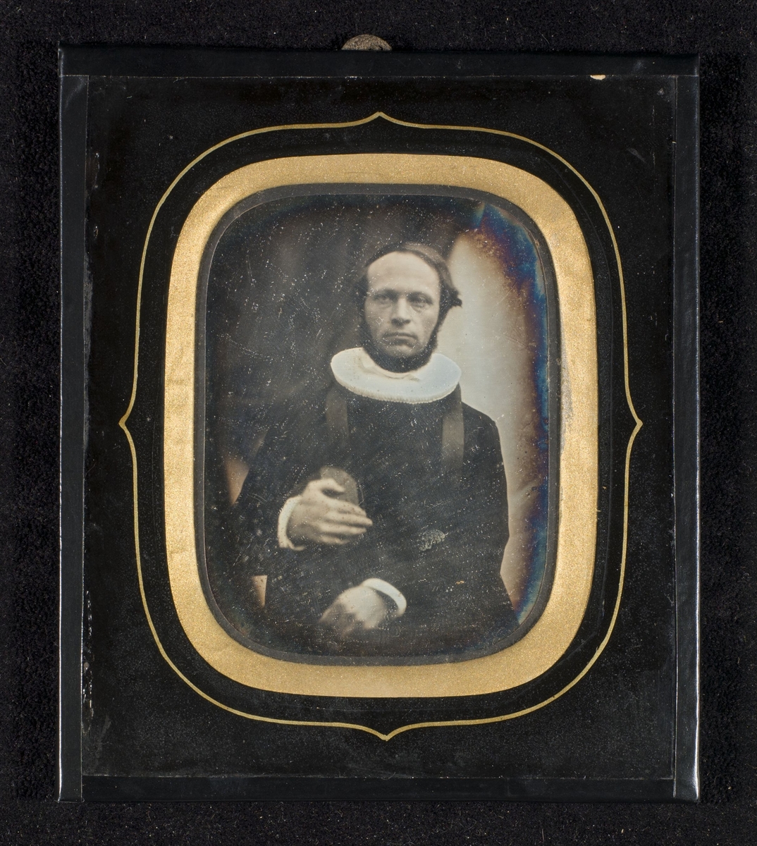 Daguerreotypi av prost Nicolai Friis (1815-1888) iført prestekjole og pipekrave. Bibel i hånden.