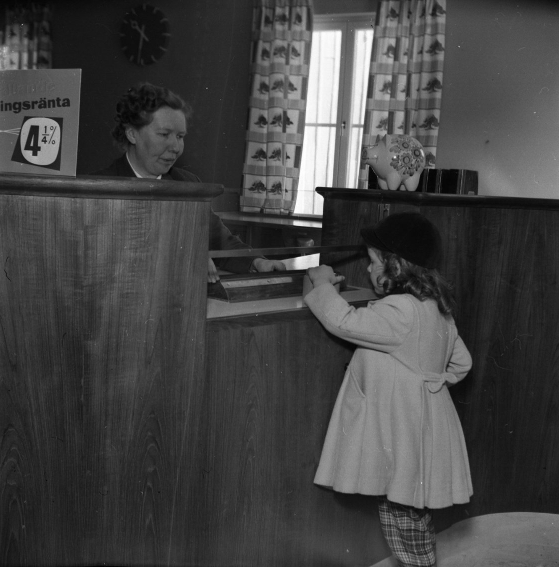 En liten flicka står vid disken på Gränna Sparbank.