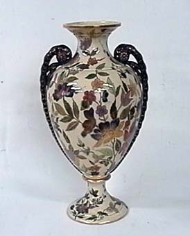 Två urnor av glaserad keramik, formad som en amfora på fot. Med flerfärgat blommönster på vit botten, och två öron.