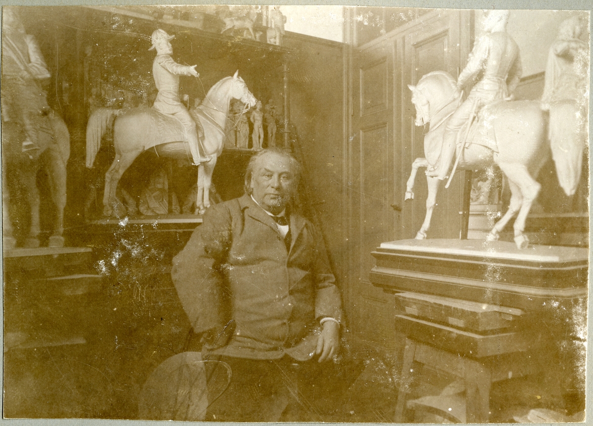 Stockholm. 
Man sittande framför gipsfigurer föreställande militärer till häst. 1901.