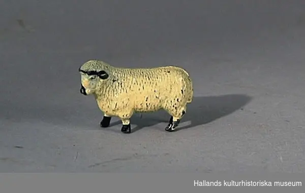Leksaksdjur - får, av gjuten metall. Naturalistisk målad i gulvitt med svarta detaljer. Stämplar: "Horny series".