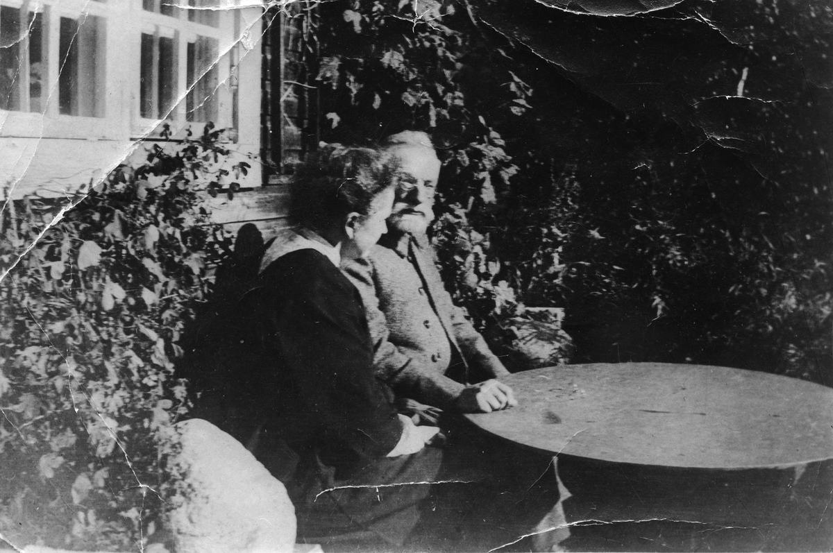 Ekteparet Ellisif og Andreas Bredal Wessel fotografert sittende ved et bord, i hagen på Turmo, Otta.