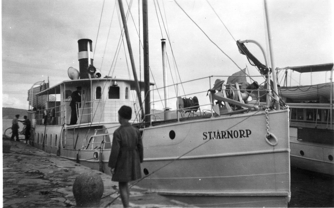 Motoriserade ångbåten M/S Stjärnorp, troligen vid kaj nedanför Visingsborgs slottsruin på Visingsö. Passagerare ombord, barn och vuxna.