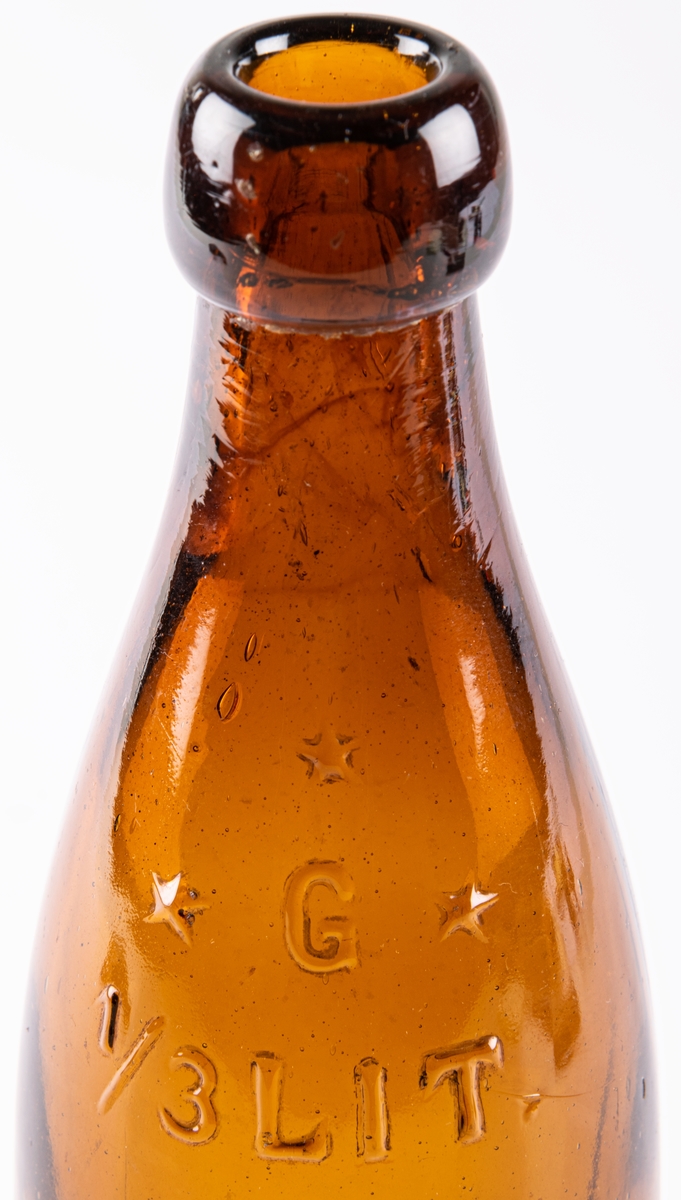 Butelj, så kallad "halva öl". Brunt glas. Märke i relief på sidan:
G (omgärdat av 3 stjärnor)
1/3 Lit.
