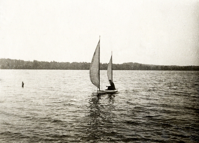 En man (i studentmössa) i en segelbåt.