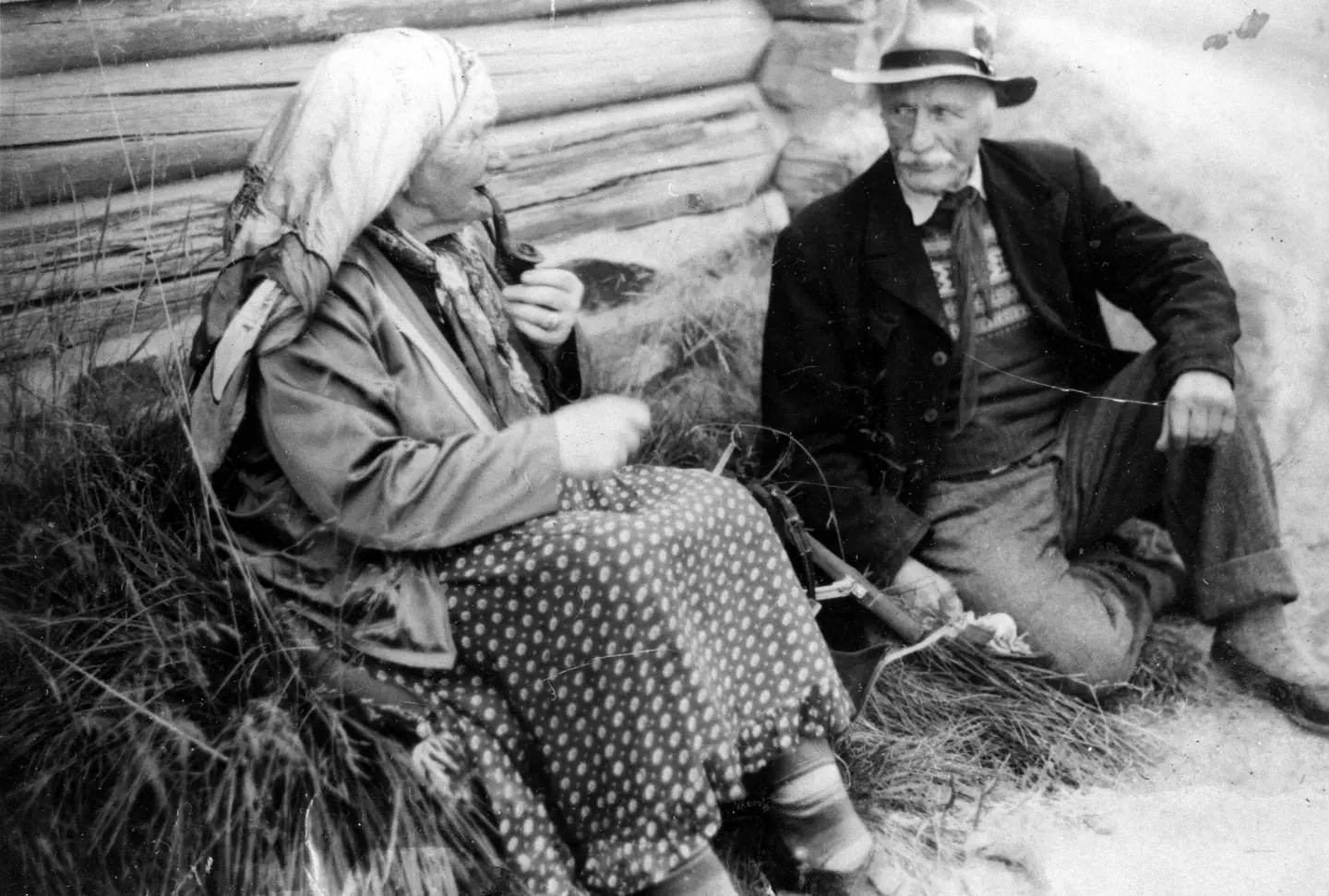 Aksel and Karoline Johansen rest by a log wall.