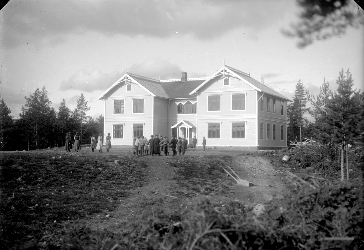 Elever og lærer i aktivitet foran skolebygning. Nybergsund skole, som brant ned etter bombingen 11. april 1940.