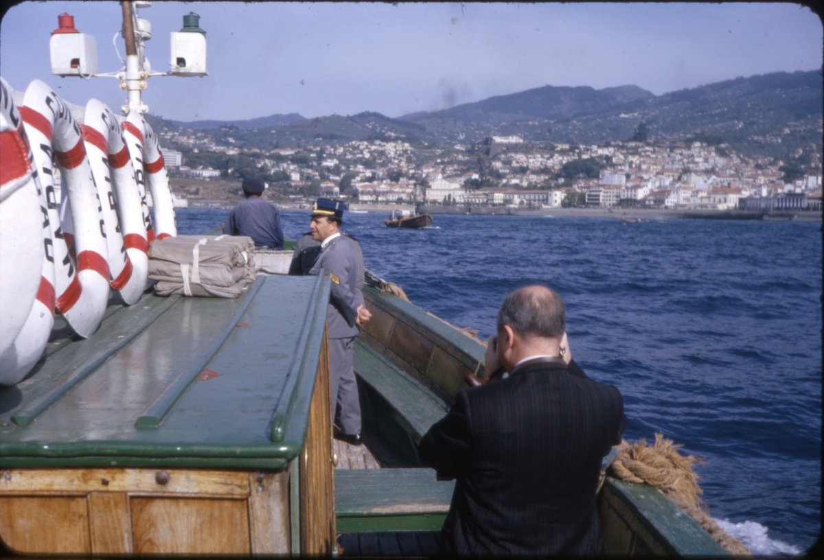 Turist og uniformert kystvakt i båt ved innfart til Funchal, Madeira. 'Sagafjord' Spring Cruise to Europe 1966.