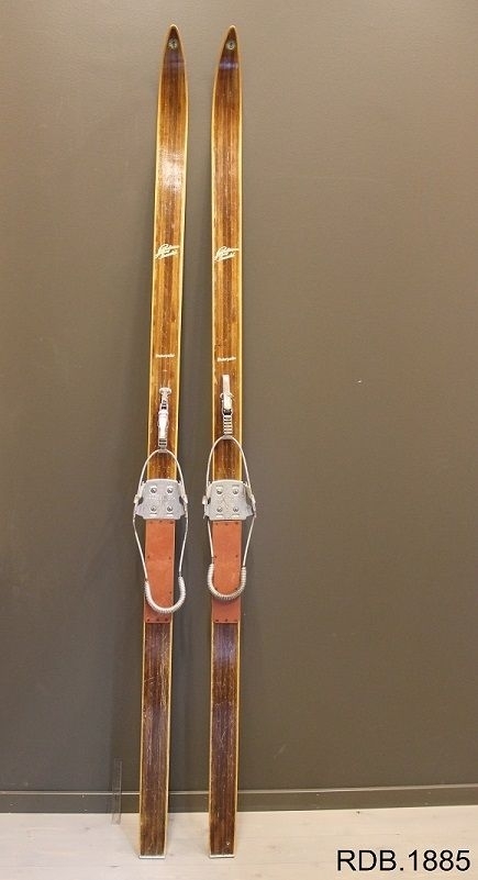 Tilnærmet jevnbred ski med liten bue. Bøy uten tupp. Rett avskåret bakende med metallforsterkning. Gresshoppa binding med wire, Made in Norway. Fotplate.

Dette er et par, og alle opplysninger og innsrkfter gjelder begge ski.