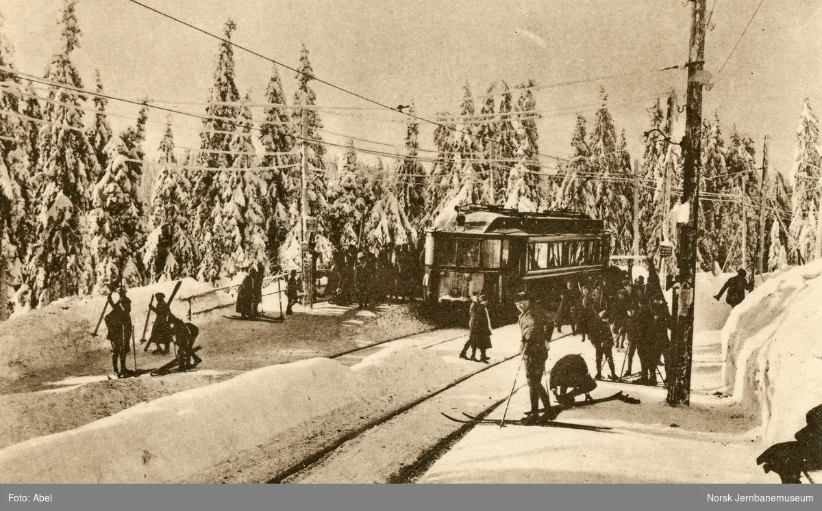 Skiløpere på Frognerseteren stasjon. En av banens motorvogner type 1914 kjører inn på stasjonen