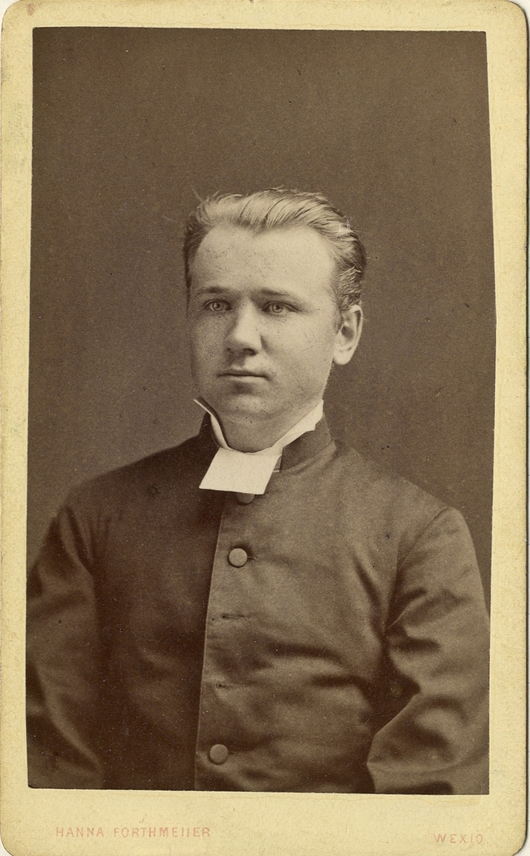 Porträttfoto av en man i prästdräkt m.m.
Bröstbild, halvprofil. Ateljéfoto.