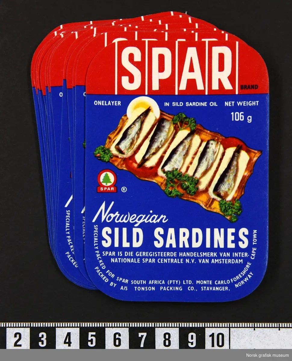 Etiketter med blå og rød bakgrunnsfarge, og illustrert med et fat med sardiner dandert med persille og tomat. 

"Norwegian sild sardines"