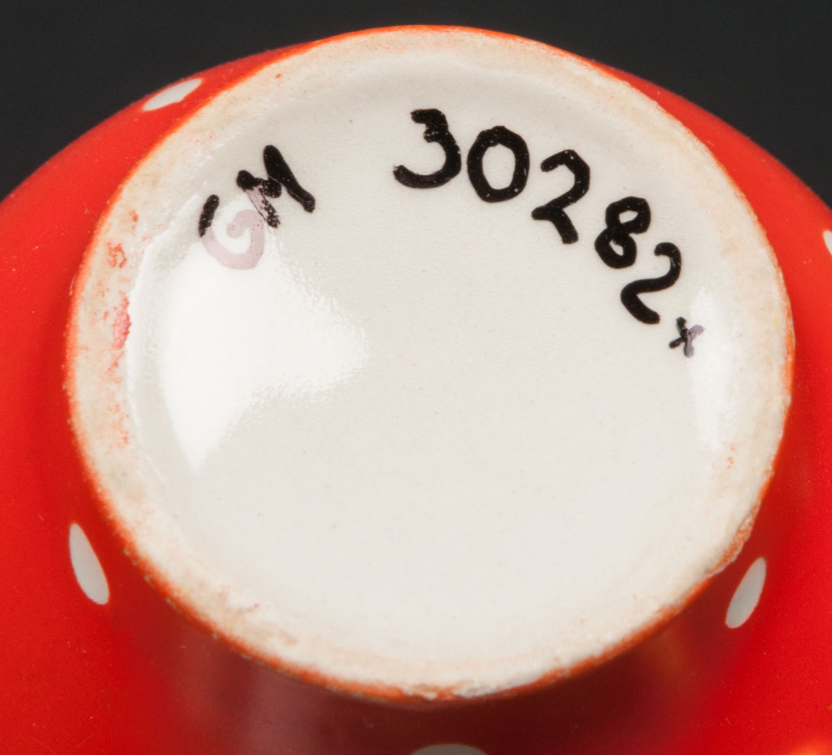 Kaffefat (med tillhörande kopp och assiett) tillverkad vid Gefle Porslinsfabrik AB. Röd bottenfärg med vita prickar. Dekorens namn "Amanita" formgiven av Helmer Ringström. Koppens modell förmodligen formgiven av Arthur Percy.