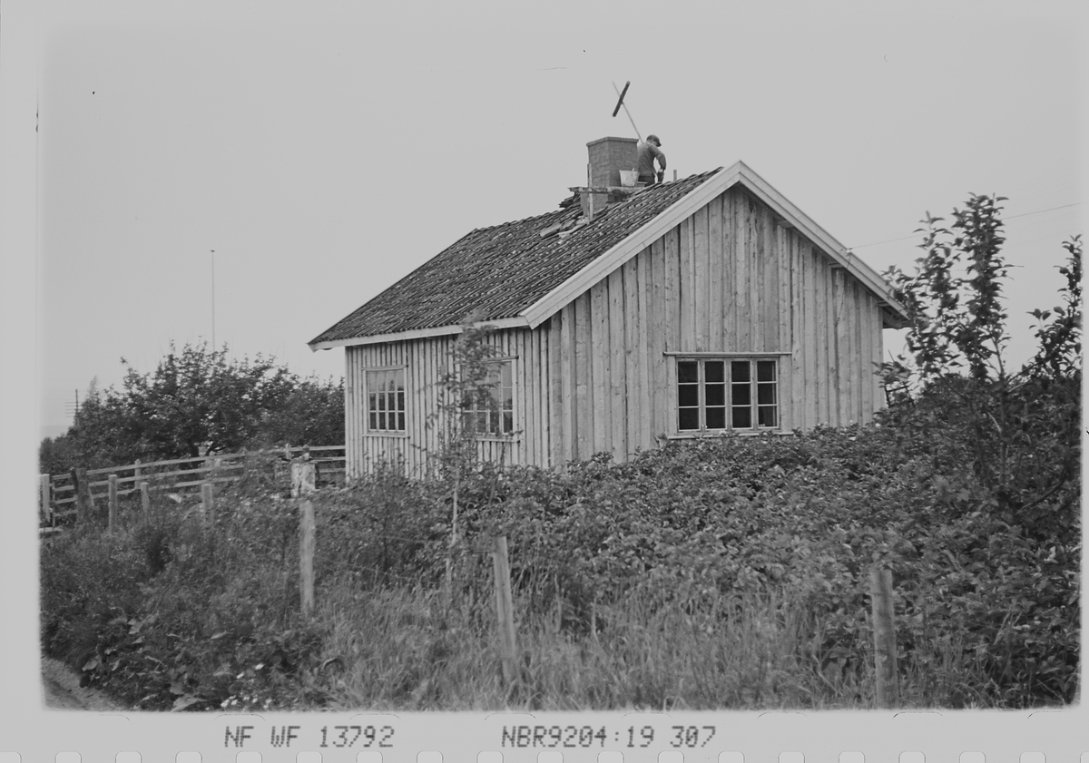 Mann som reparerer taket på liten bolig. Haugsbygda, Ringerike. Fotografert 1940.