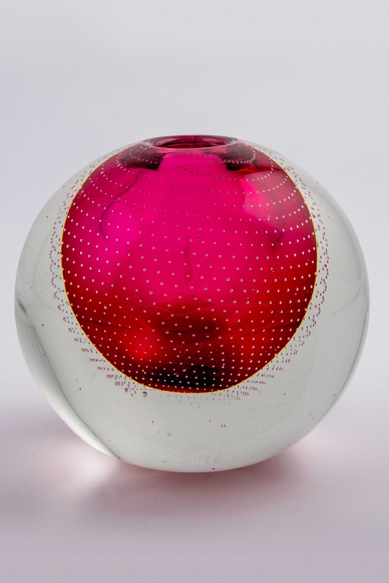 Glassvase i underfangsteknikk. Eggeformet koprus med et rosa sjikt innerst, omgitt av en tykk klar glassmasse. Liten sirkulær åpning. Korpus er dekorert med rekker av små luftbobler som danner et spiralformet mønster.