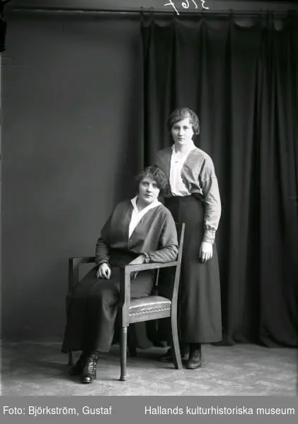 Ateljébild med två kvinnor, den ena sittande i en karmstol. Tidigt 1900-tal. Beställare, och troligen en av kvinnorna på bilden, är Rosa Ljungnell.