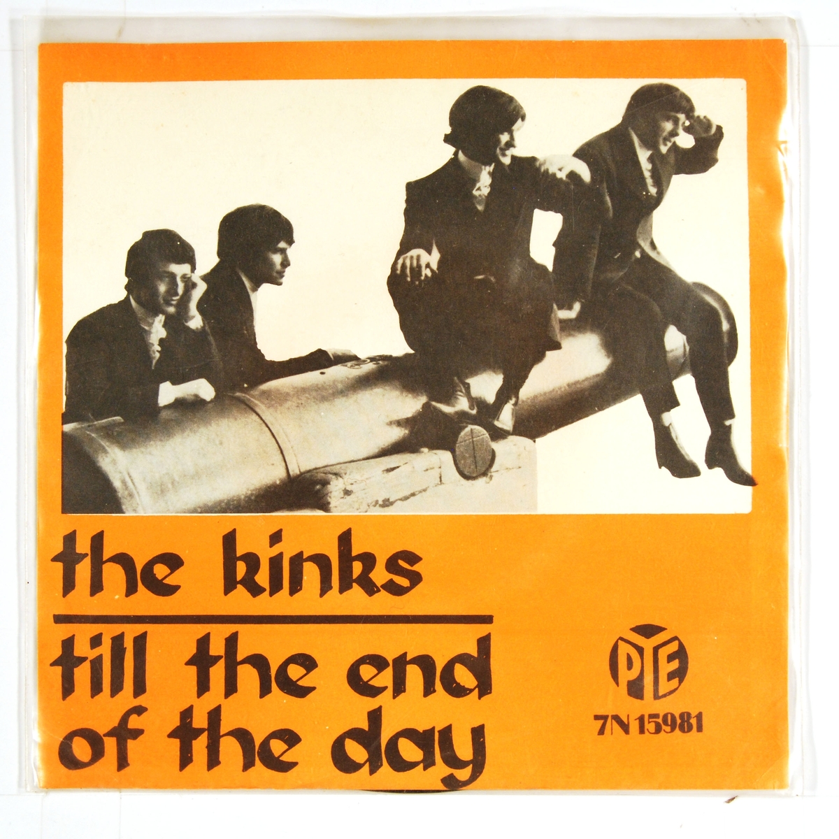 Bilde av medlemmene i "The Kinks" som står ved og sitter på en kanon.