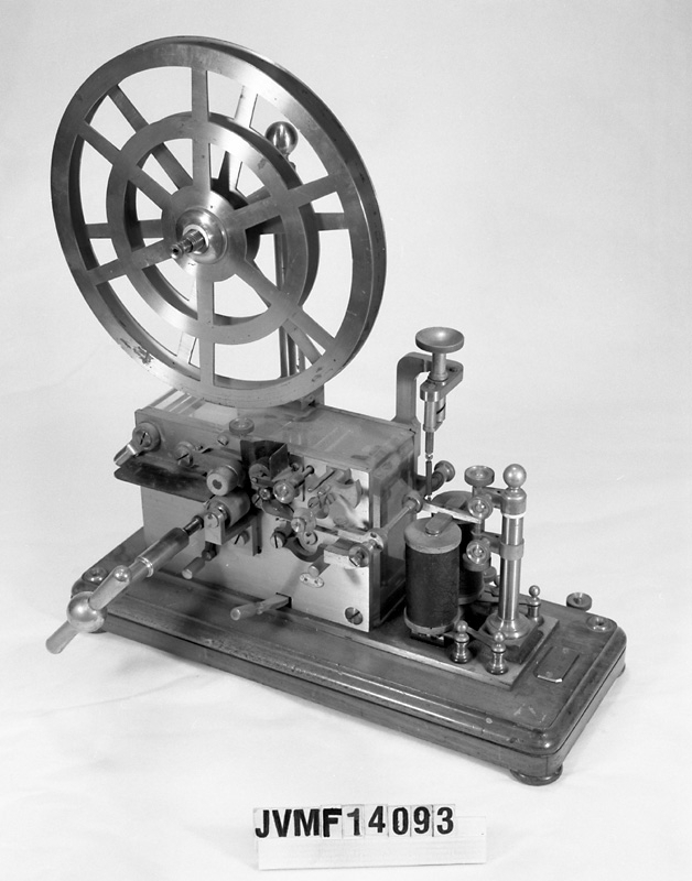 Morsetelegraf med sockel av trä och genombrutet telegrafhjul av mässing.