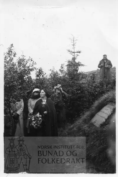 Klara Semb legg ned krans ved grava til Hulda Garborg. Klara Semb kledd i bunad, dei andre i motedrakt.