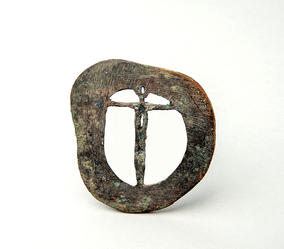 Bronsföremål, möjligen ett spänne eller medaljong av brons. Föremålet är 7,5x7 cm och har form av en kristusfigur infälld i en gjuten ram.