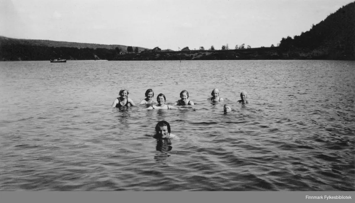 Åtte kvinner svømmer i elvemunningen i Neiden. Tidspunkt er rundt 1930-1940.