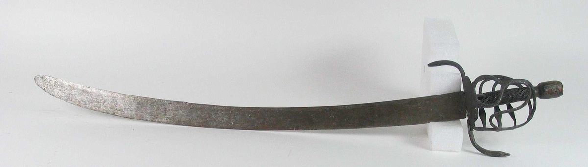 Rund tønneformet knapp i tre. Asymmetrisk feste med tre sidebøyler som har fortykninger på midten på utsiden og tommelbøyle og to sidebøyler på innsiden. Nyreformede parérplater. S-formede runde parérstenger med fortykkede avslutninger på endene. Fremre parérstang er nyere.
Tregrep med jerntrådvikling.
Enegget krum kline med smal ryggstillt blodrand. Smedmerke på venstre side. Klingespissen er dekorert med tre små hull.