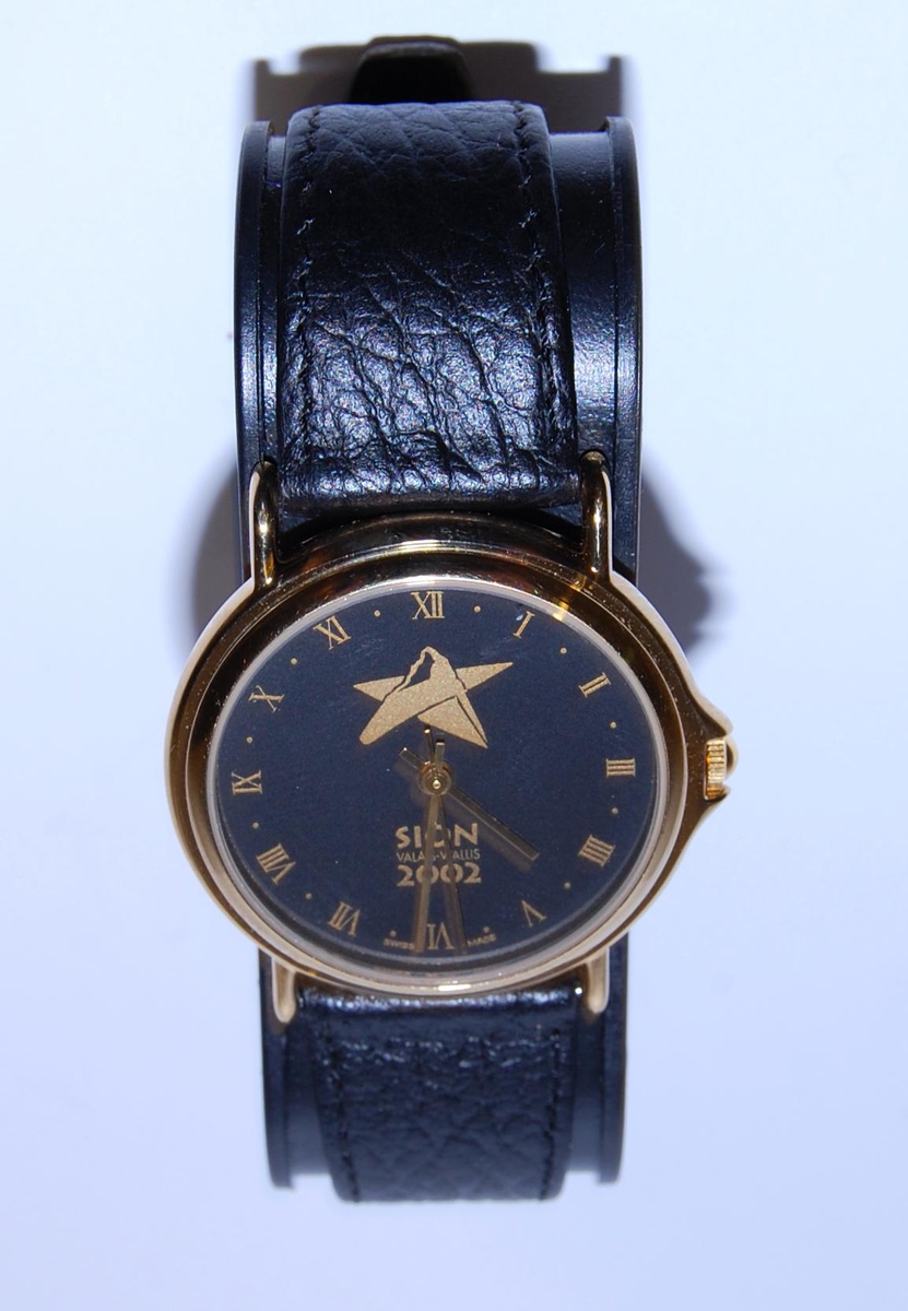 Gull- og sortfarget armbåndsur med emblem for kandidatbyen Sion, i forbindelse med søkerprosessen til de olympiske vinterleker i 2002. 