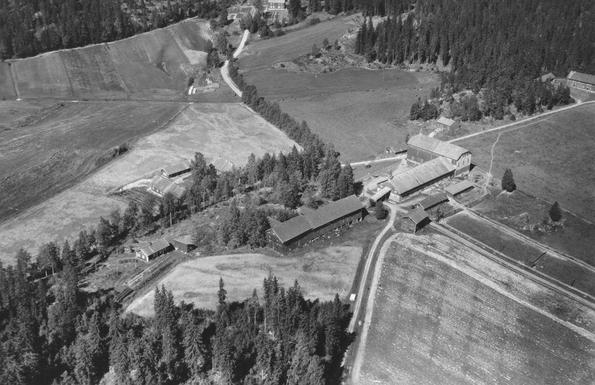 Flyfoto av driftsbygningene på Losby bruk. Skolehuset bak.