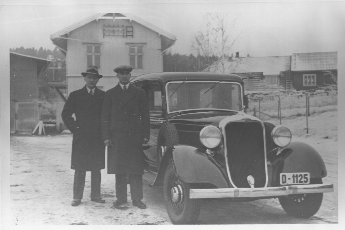 To menn stående ved siden av en Strømmen-produsert Dodge 1933.