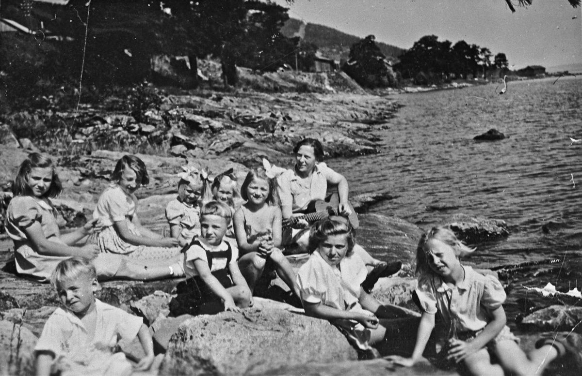 Barn og en voksen i strandkanten ved Mjøsa, på Morskogen Sommeren 1947. Søndagsskolen på strandtur.