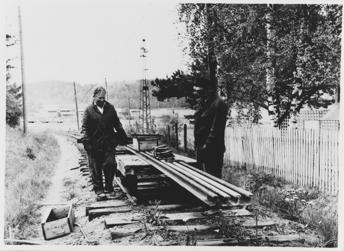 Riving av Urskog-Hølandsbanens spor på Bjørkelangen. Arbeidet utføres med håndkraft, og skinnemateriellet kjøres inn med håndtralle. Hans Bådahl t.v.
