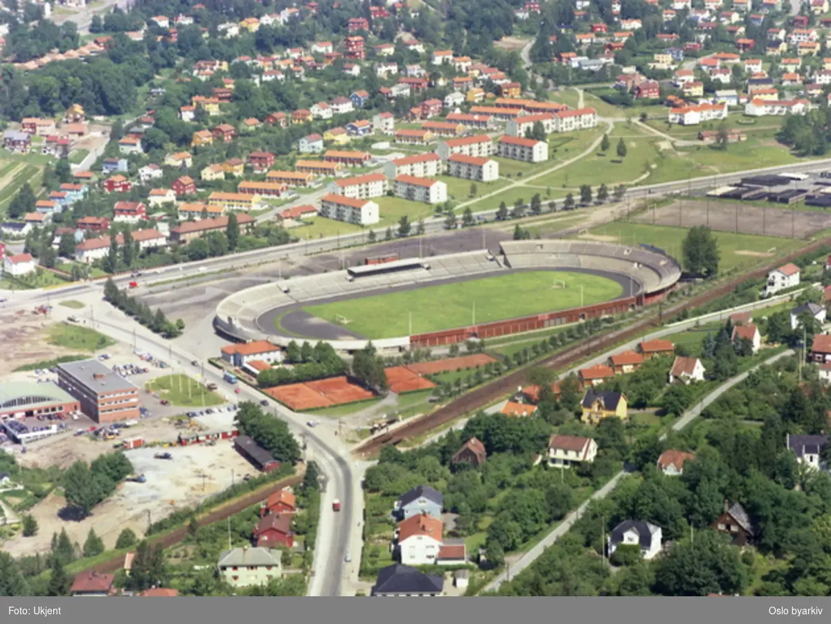 Ullevål stadion, Ringveien bak og Sognsveien til venstre. Møllesvingen og Bergslia tar av fra Songsveien mot høyre. Trikkesporet til Sognsvannsbanen passerer stadion. Boligblokker og villabebyggelse på Sogn og Norberg i bakgrunnen. (Flyfoto)
